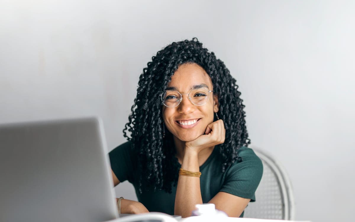 Happy woman sitting at table with laptop